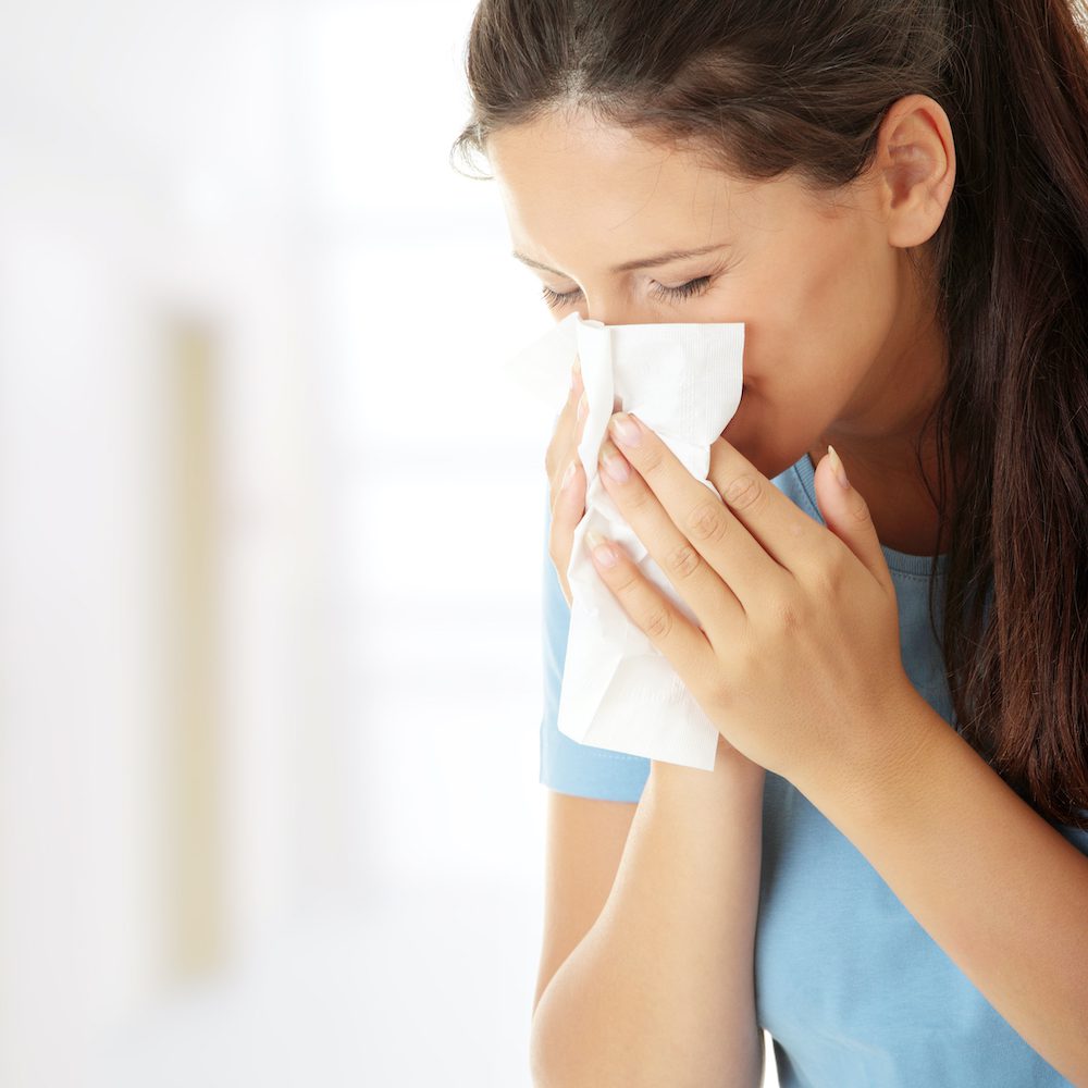 Woman with a tissue, likely sick or experiencing allergies.