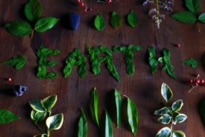 "EARTH" spelled with leaves on wood, surrounded by other leaves.