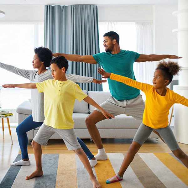 Family comfortably doing yoga in their living room because of the lack of indoor pollutants from indoor air quality equipment installed by CPS HVAC